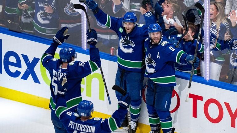 Vancouver Canucks' Carson Soucy, back left, J.T. Miller, back right,...