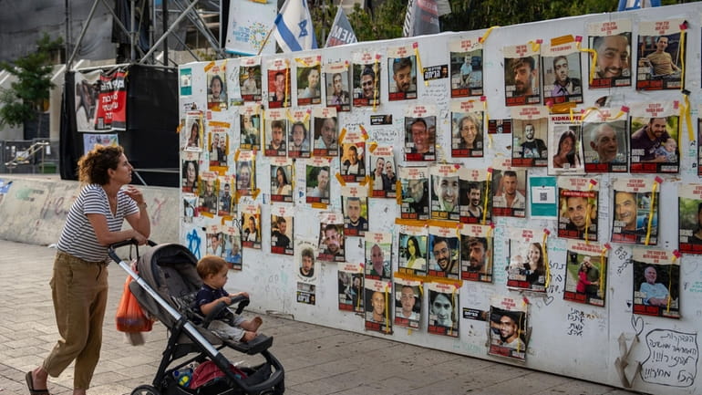 Passersby observe the photos of hostages held in the Gaza...