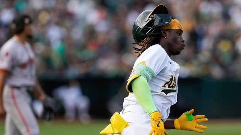 Oakland Athletics' Lawrence Butler, right, runs after hitting a double...