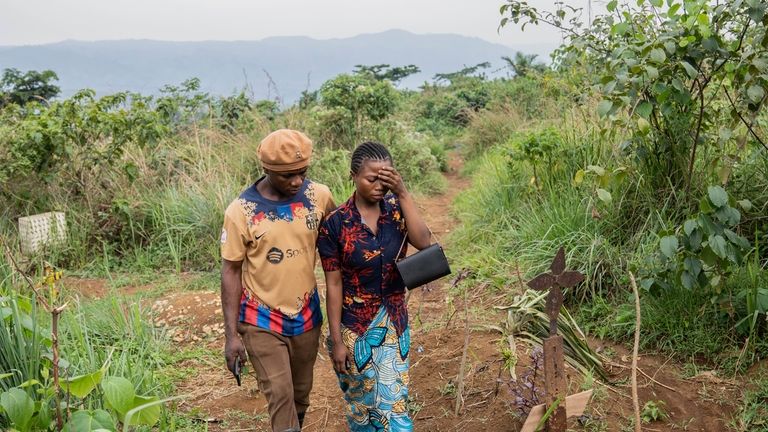 Olivier and Divine Wisoba walk by the grave of their...