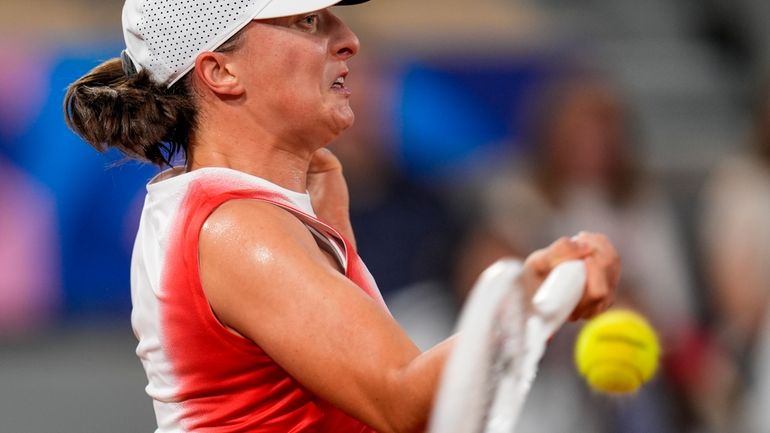 Iga Swiatek of Poland returns the ball against Irina-Camelia Begu...