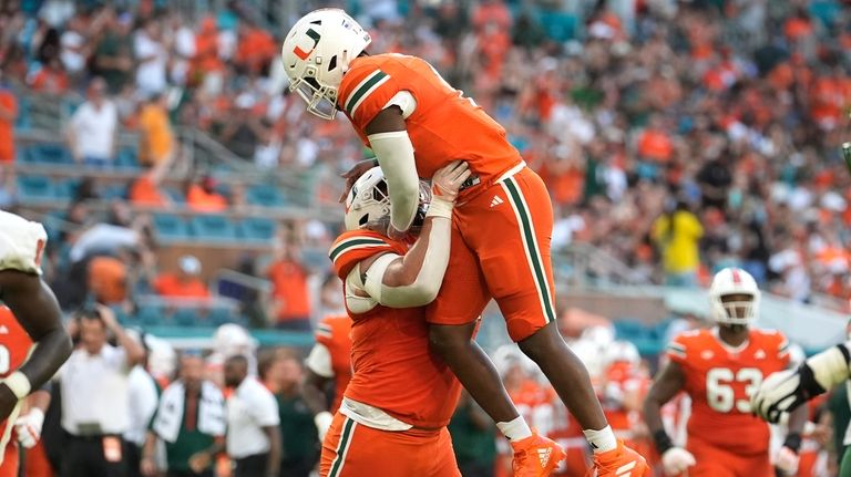 Miami offensive lineman Francis Mauigoa, left, lifts quarterback Cam Ward...