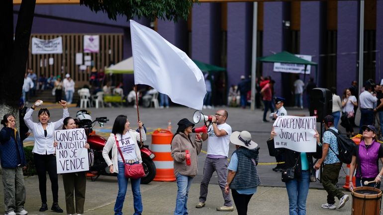 Unionized federal court workers hold signs and shout slogans as...