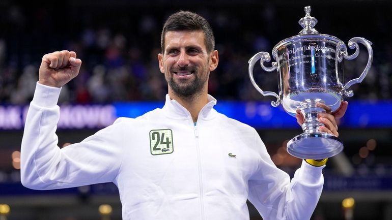 Novak Djokovic holds up the championship trophy after defeating Daniil...