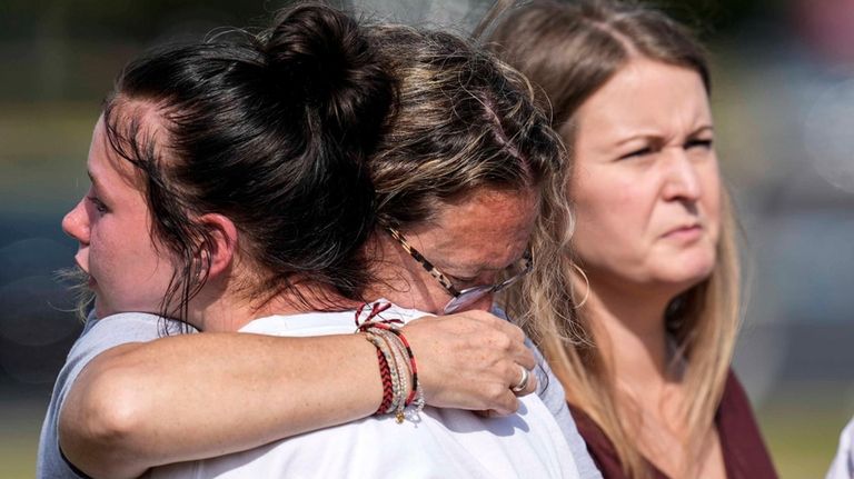 People embrace at a makeshift memorial after a shooting Wednesday...