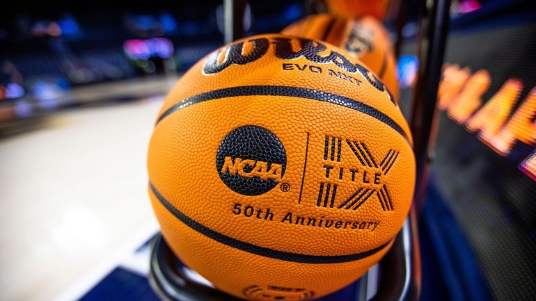 FILE- A basketball with an NCAA logo and a Title...