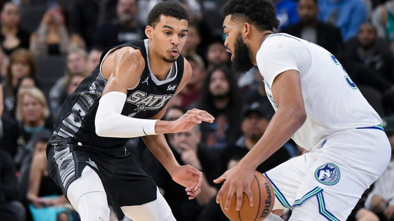 Minnesota Timberwolves' Karl-Anthony Towns, right, drives against San Antonio Spurs'...