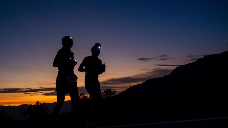 A runner and their pacer run as the sun rises...