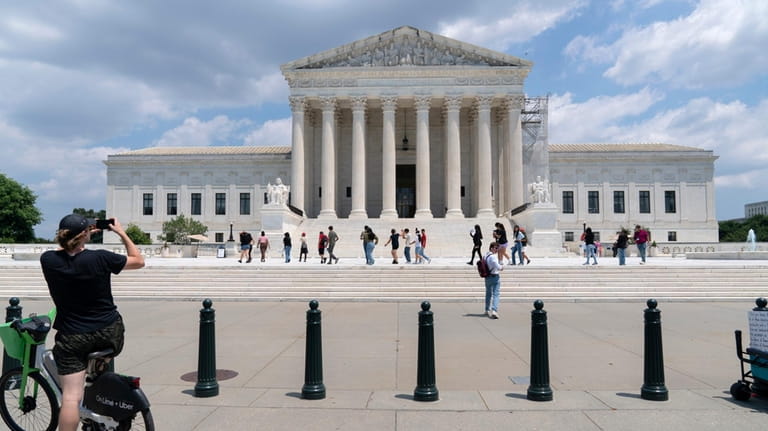 Visitors pose for photographs at the U.S. Supreme Court Tuesday,...