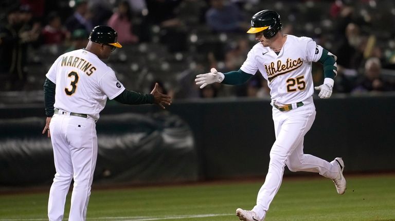 Oakland Athletics' Brent Rooker (25) is congratulated by third base...