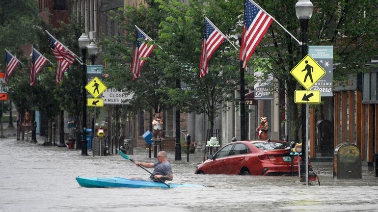 A kayaker paddles across Main Street in downtown Barre, Vt.,...