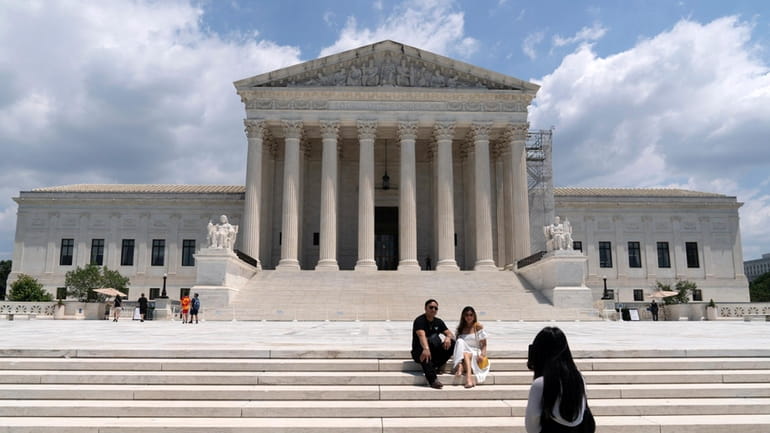 Visitors pose for photographs outside the U.S. Supreme Court Tuesday,...