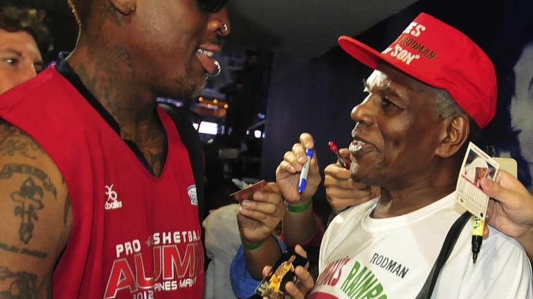 Former NBA star Dennis Rodman, left, shakes hands with his...