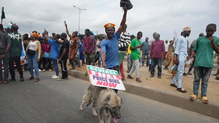 A man with his dog gather with others to protest...