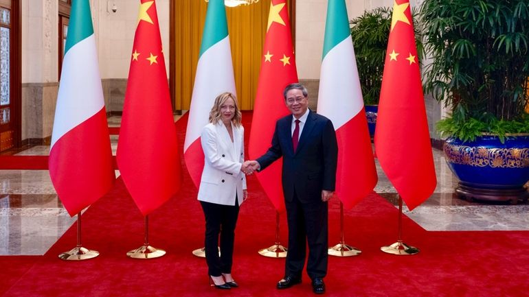 Italy's Prime Minister Giorgia Meloni shakes hands with Chinese Premier...