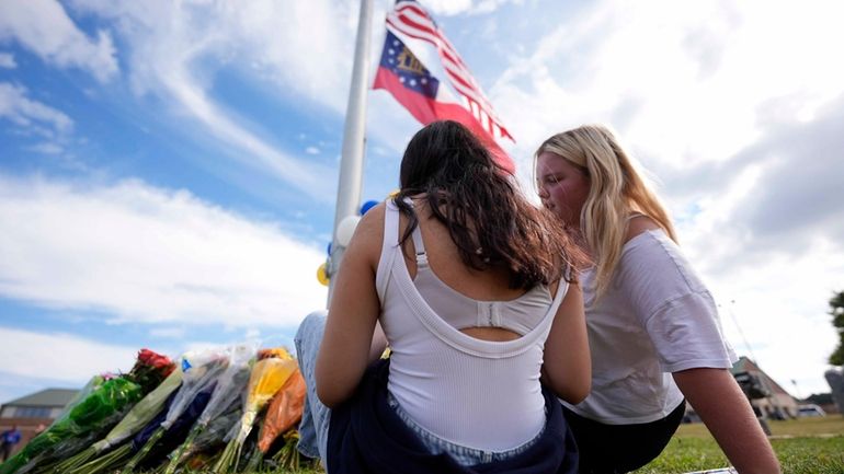 Two students view a memorial as the flags fly half-staff...