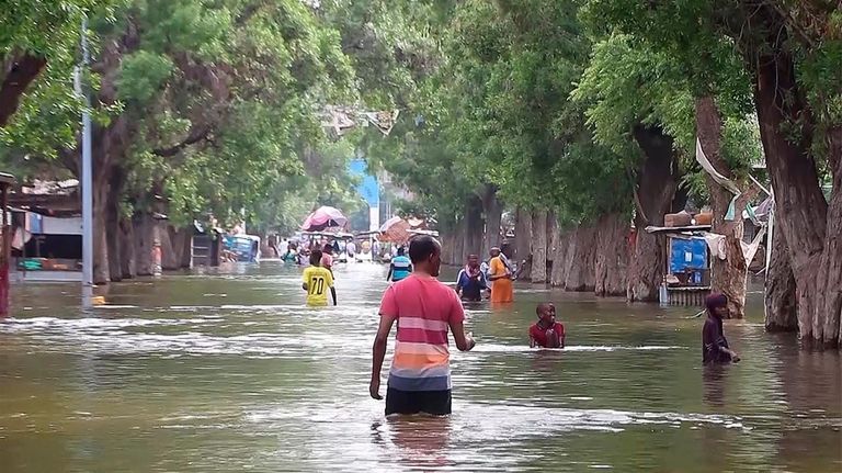 In this image made from video, residents move through floodwaters...