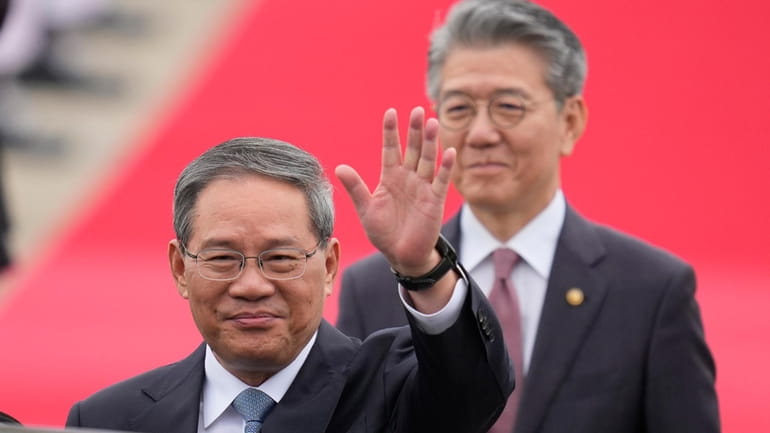 Chinese Premier Li Qiang, left, waves to media members before...