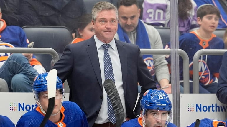 Islanders' head coach Patrick Roy, center right, watches the action...