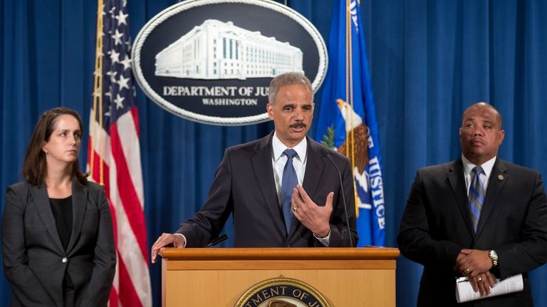 Attorney General Eric Holder, center, speaks during a news conference...