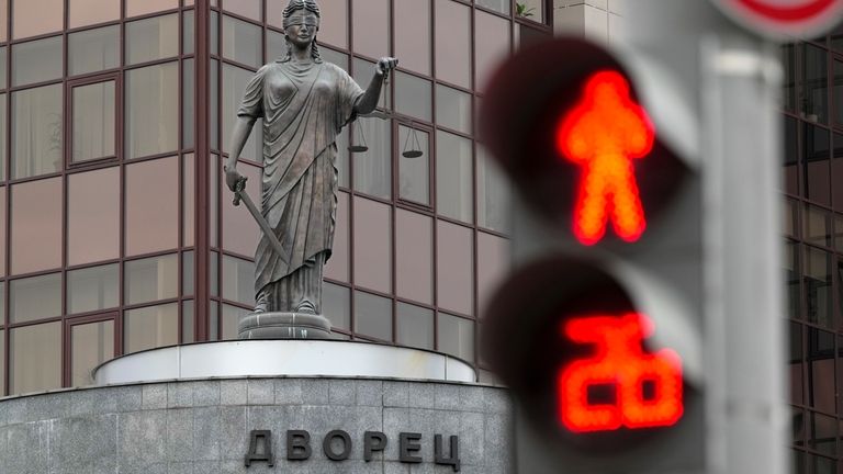 The Lady Justice statue is seen through a traffic light...