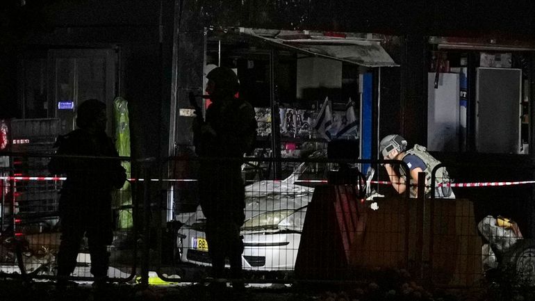 Israeli security forces examine a car after an explosion at...