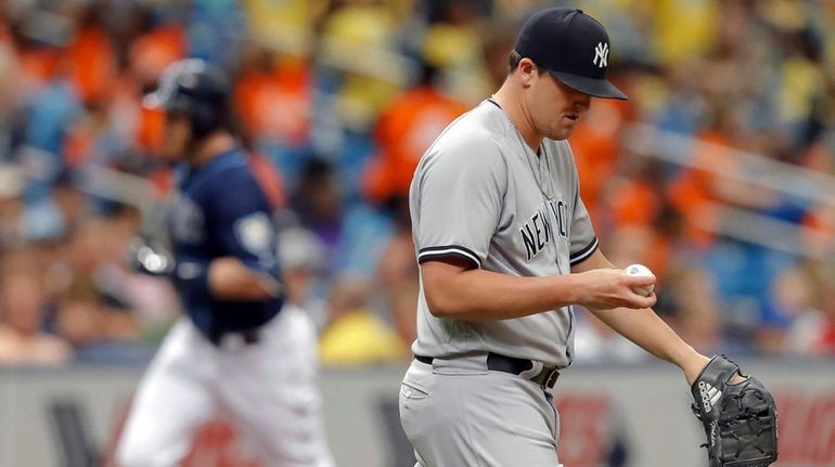 Yankees relief pitcher Jonathan Holder reacts after giving up a...