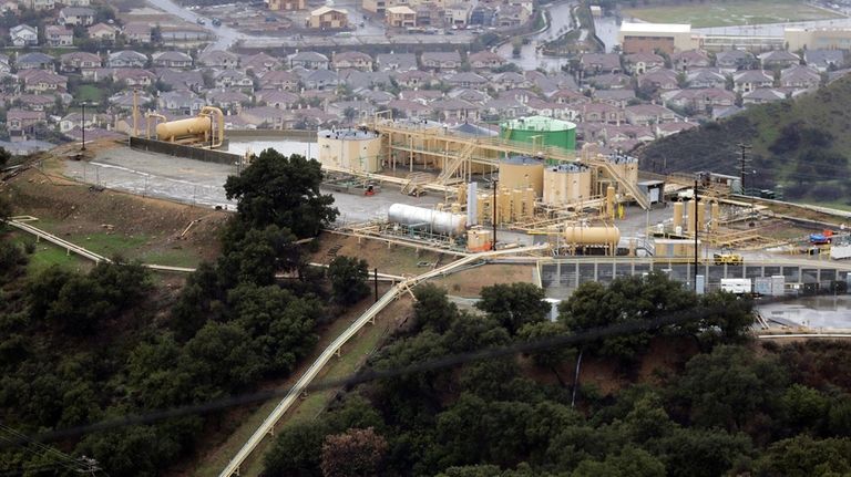 A gas gathering plant sits on a hilltop at the...