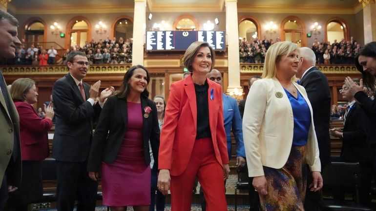 Gov. Kim Reynolds, center, is escorted into the House of...