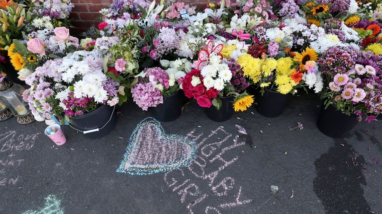 Floral tributes are left at the site in Southport, England,...