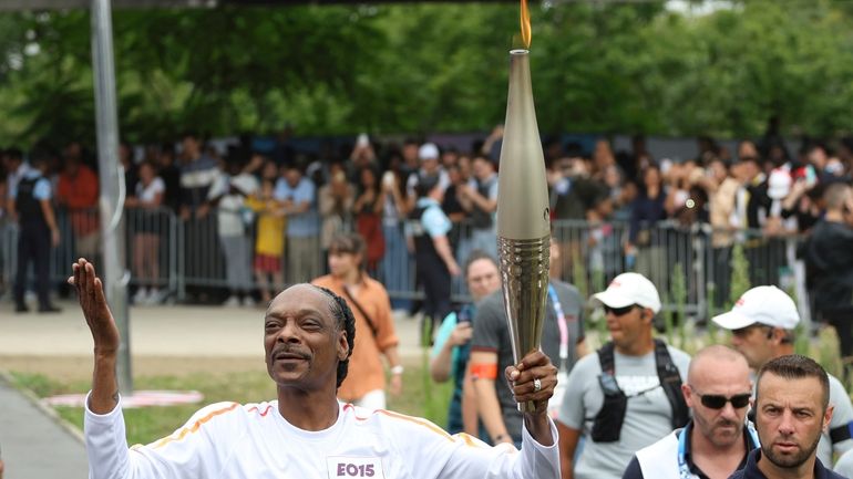 Snoop Dogg carries the Olympic torch at the 2024 Summer...