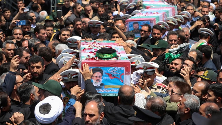 Mourners crowd around the flag-draped coffins of Iranian President Ebrahim Raisi...
