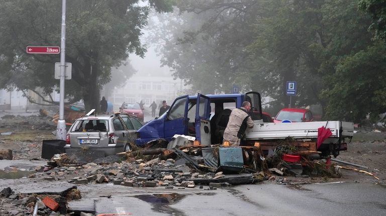 A resident looks at his damaged car after recent floods...