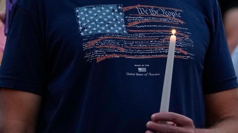 A man holds a candle during a vigil for Corey...