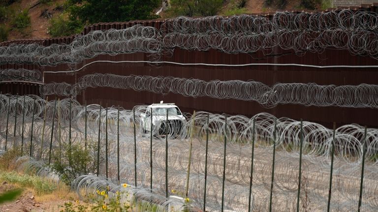 A vehicle drives along the U.S. side of the US-Mexico...