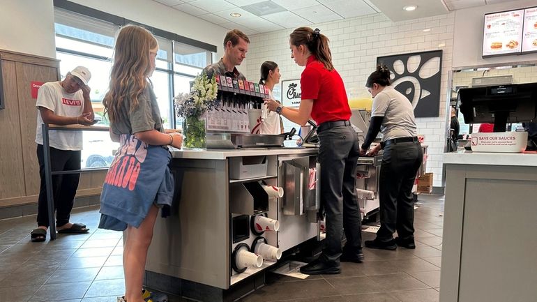 Workers serve customers at a fast food restaurant Thursday, June...