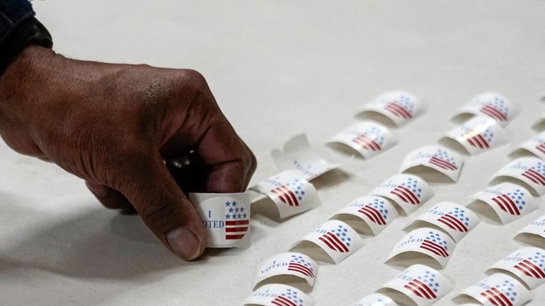 A voter picks up a sticker after voting at a...