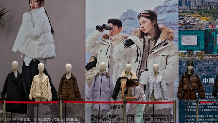 A woman sets up mannequins displaying winter clothes near a...