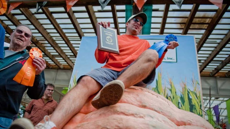 Scott Armstrong celebrates his win sitting atop his pumpkin in...