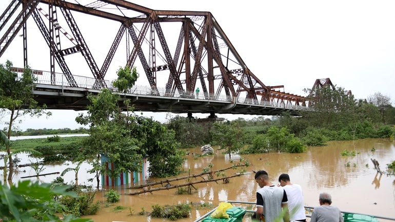 People watch the flooded Red river next to iconic Long...