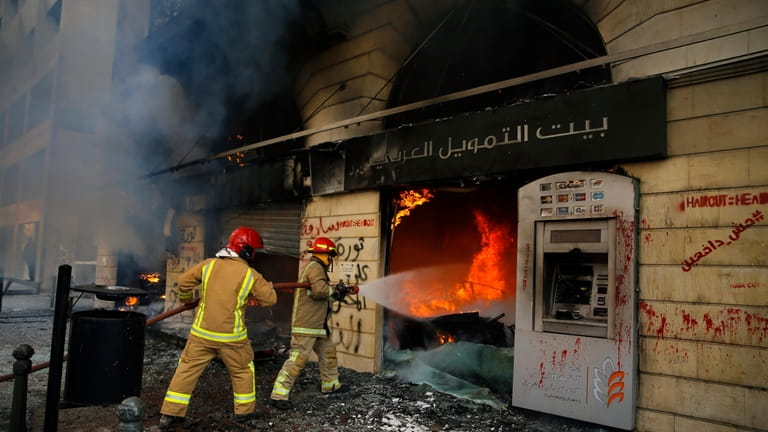 Firefighters hose the branch of the Credit Libanais Bank that...