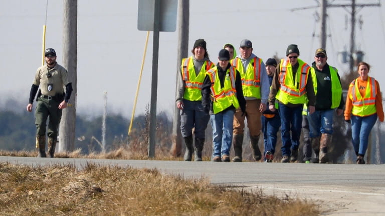 Police and area firefighters walk along state Highway 310 near...