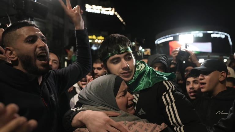 Omar Atshan, 17, is hugged by his mother after being...
