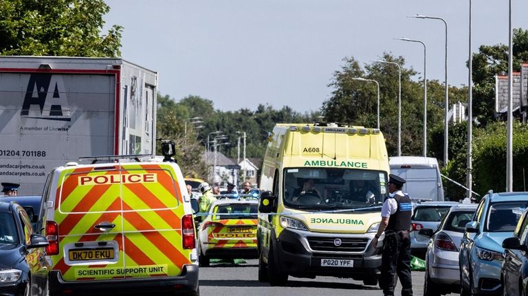 Emergency services work at the scene in Southport, England, where...