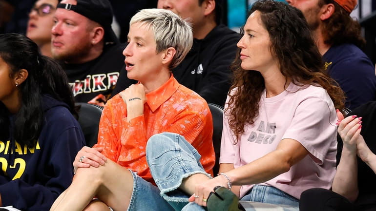 Megan Rapinoe, left, and Sue Bird, right, sit courtside during...