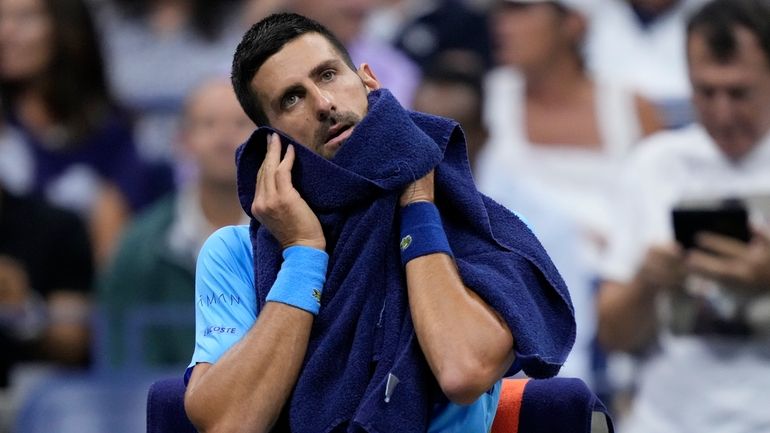 Novak Djokovic, of Serbia, wipes his face during a third...