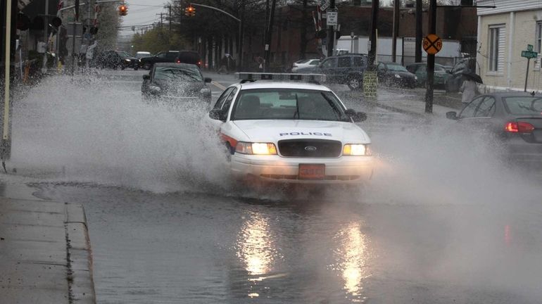 A Nassau County police car and other vehicles navigate a...