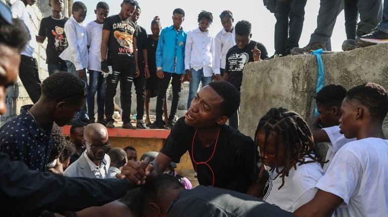 Relatives grieve during a burial service for 16-year-old Jhon-Roselet Joseph,...