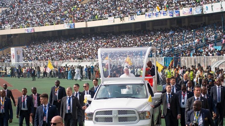 Pope Francis on the popemobile, waves at worshipers at the...