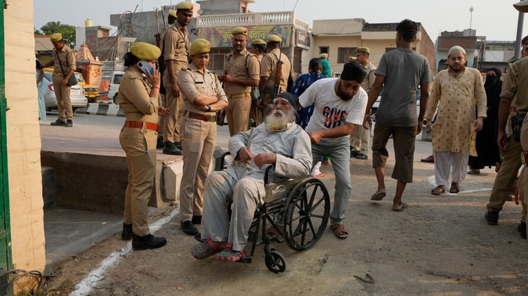 An elderly man arrives in a wheelchair to cast his...